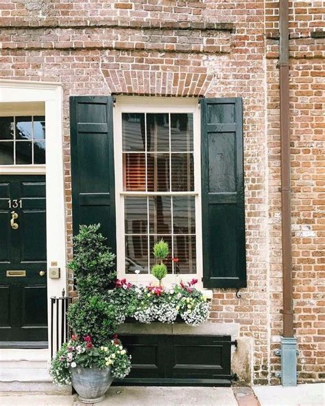 A Brick House With Green Shutters On The Front